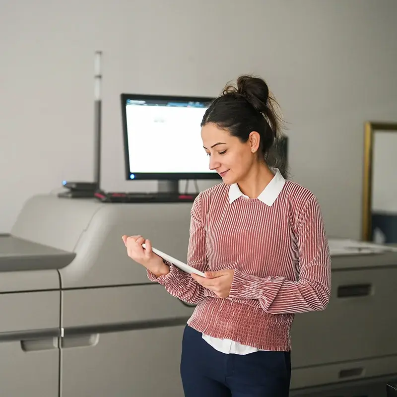Operator holding a tablet beside a Ricoh production press