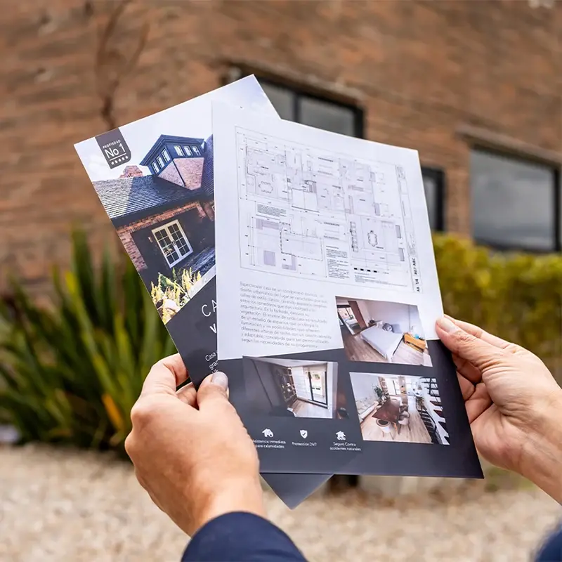 Hands holding full-colour property brochures and floor plan; strong application image.