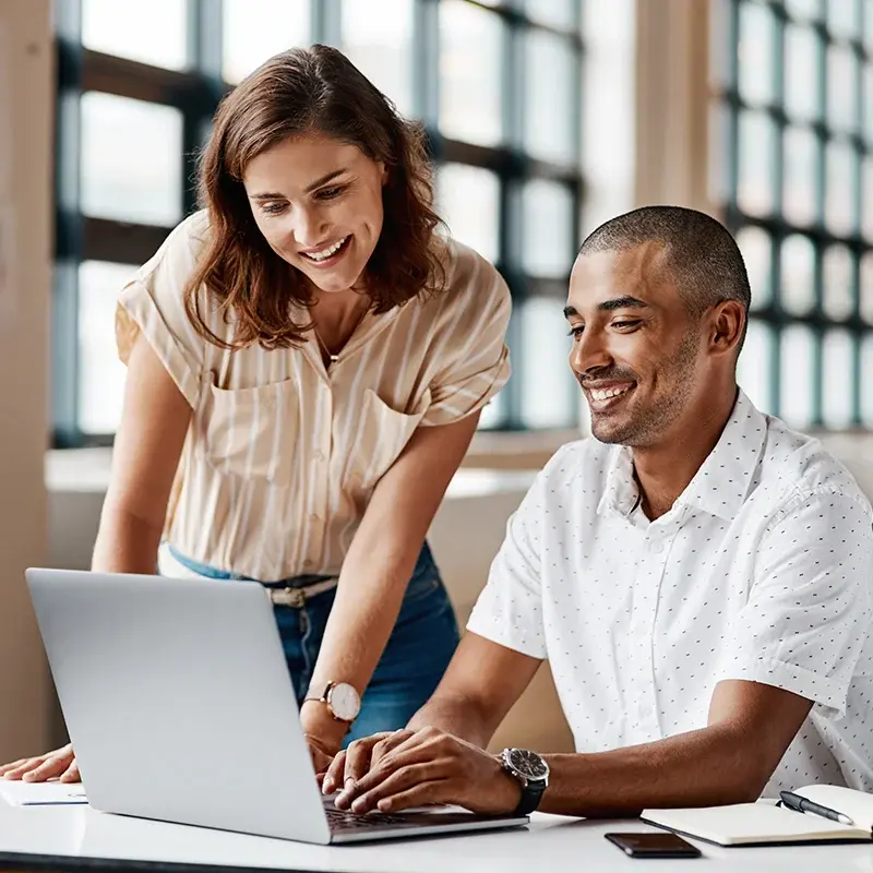 Two colleagues reviewing a laptop