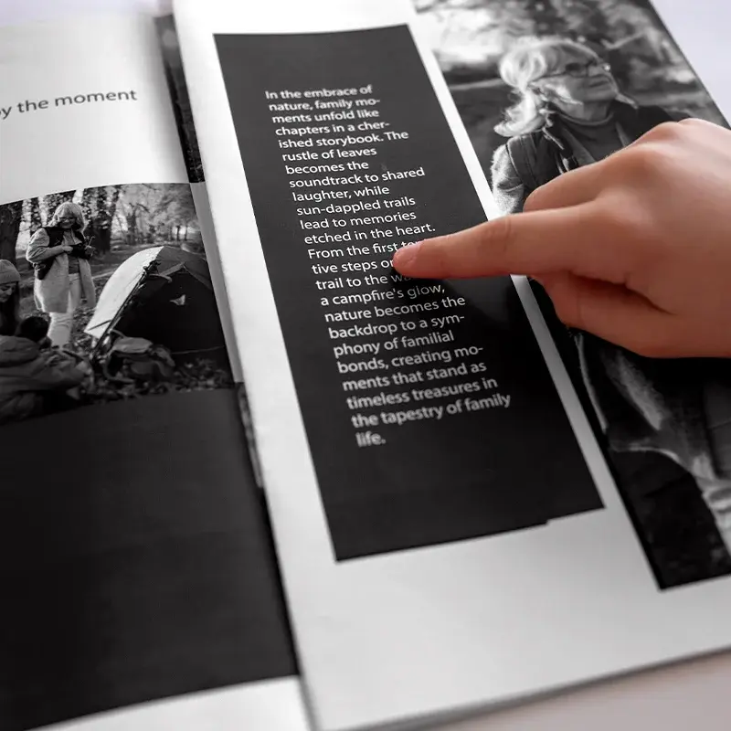 Reader holding a finished monochrome book with photograph and text