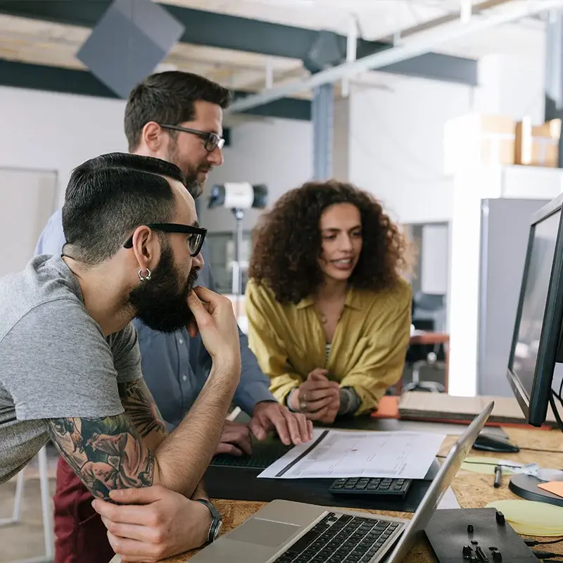 Three creative workers reviewing a computer