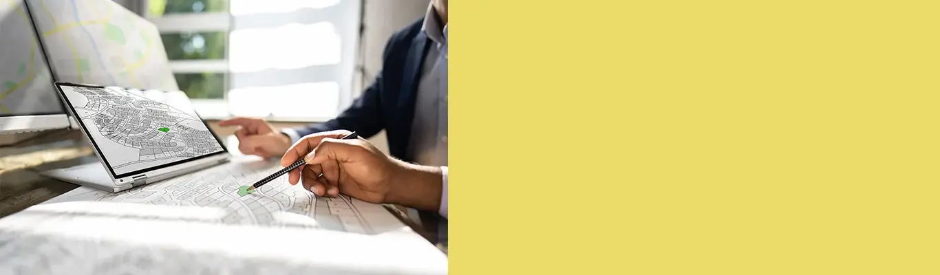 Person reviewing site plans on laptop with yellow panel