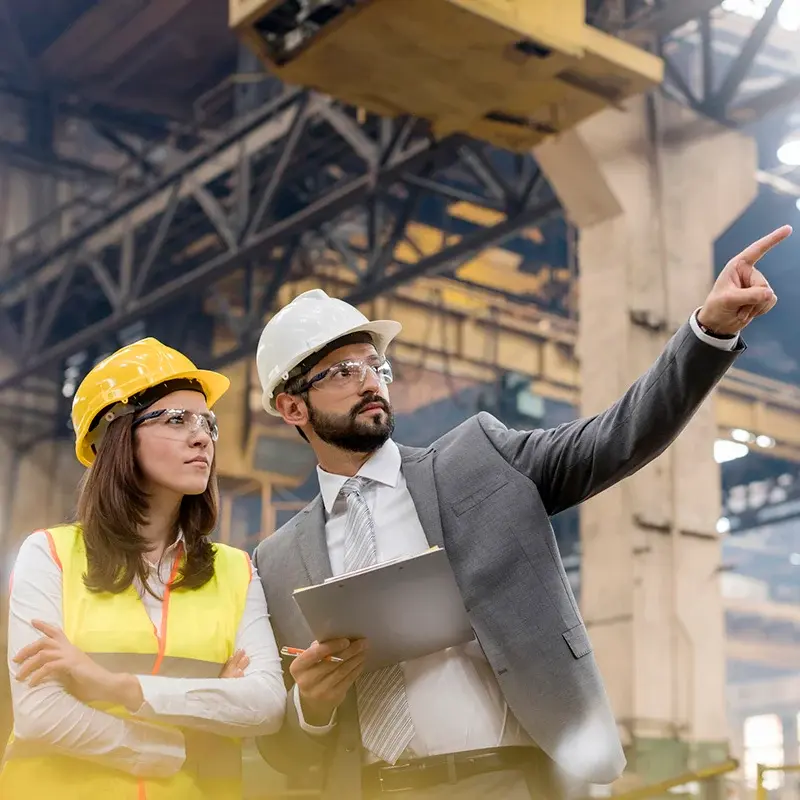 Two engineers on industrial site reviewing a tablet