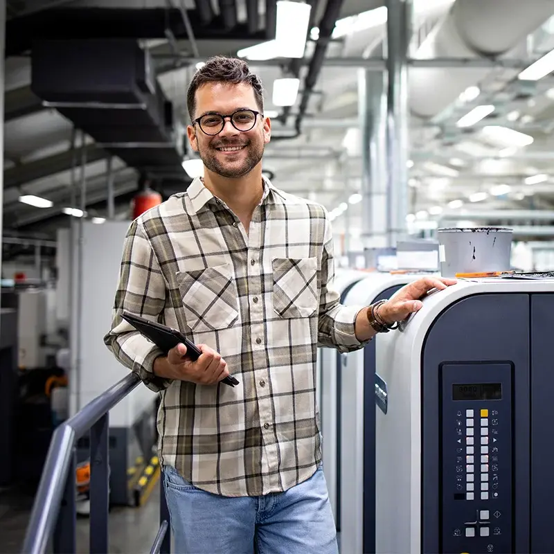 Print-room operator with tablet beside production equipment